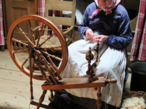糸車で糸を紡ぐ女性